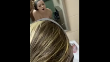 A lovely girl is bent over a restroom sink in public